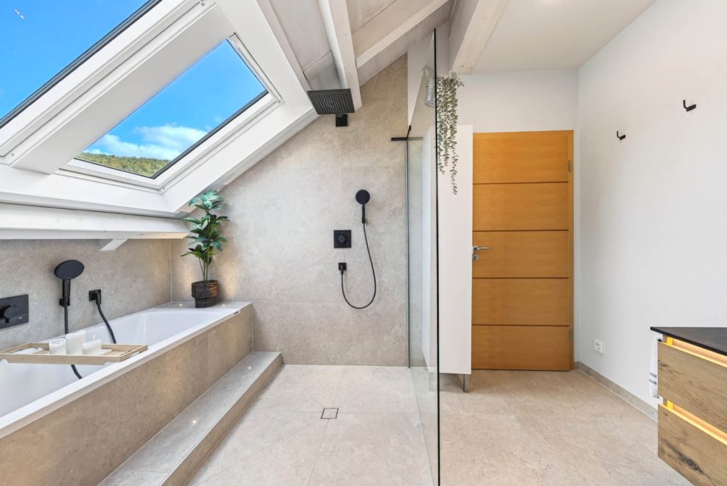Badewanne mit Stufe und bodengleiche Dusche unter zwei Dachfenstern