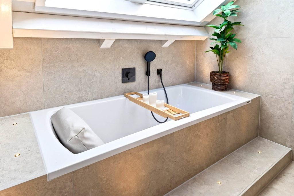 Eingebaute Badewanne mit Wannenablage aus Holz und schwarzer Handbrause