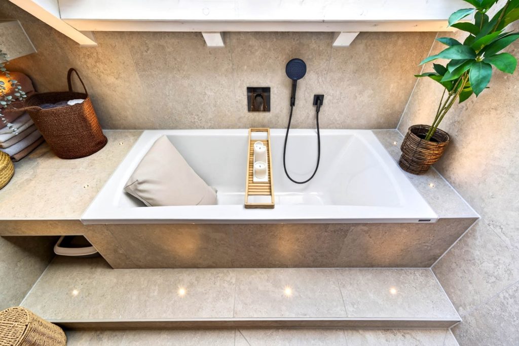 Badewanne mit Holzablage und schwarzer Brause, Stufe mit Bodenspots