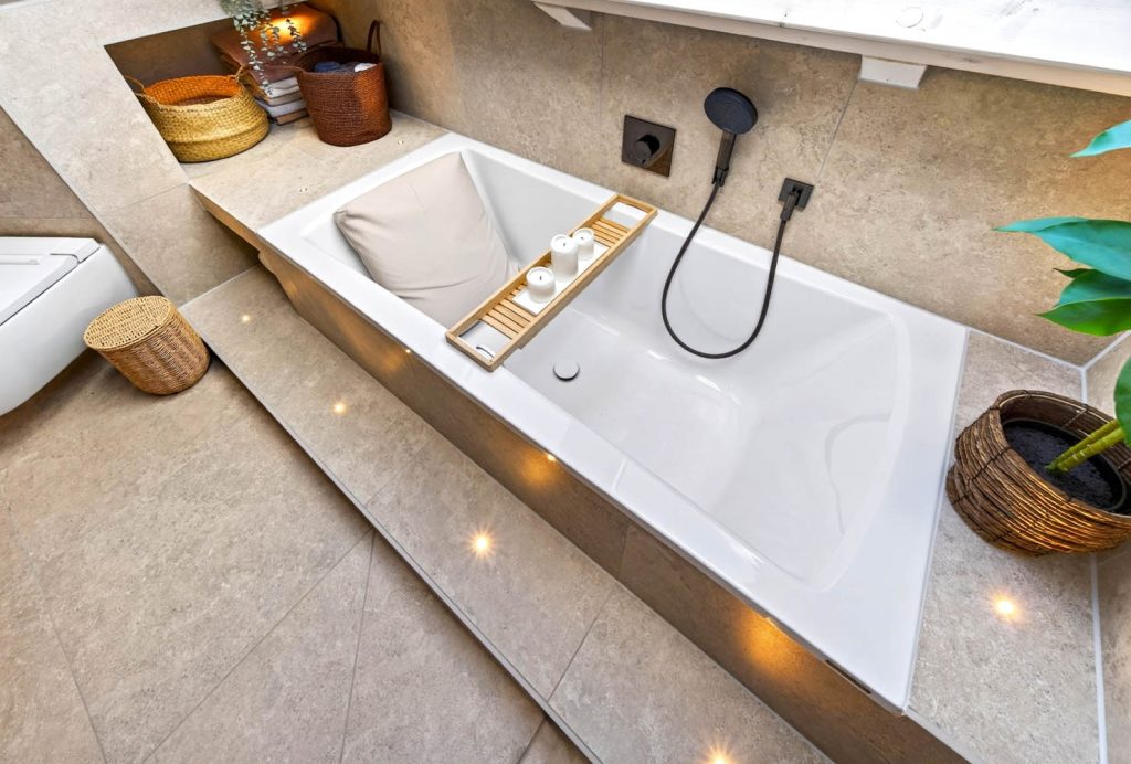 Badewanne mit beleuchteter Stufe und Pflanze im Korb