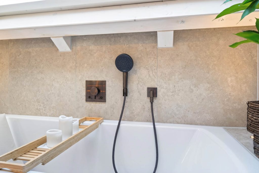 Schwarze Brause mit Wandhalter über der Badewanne mit Holzablage
