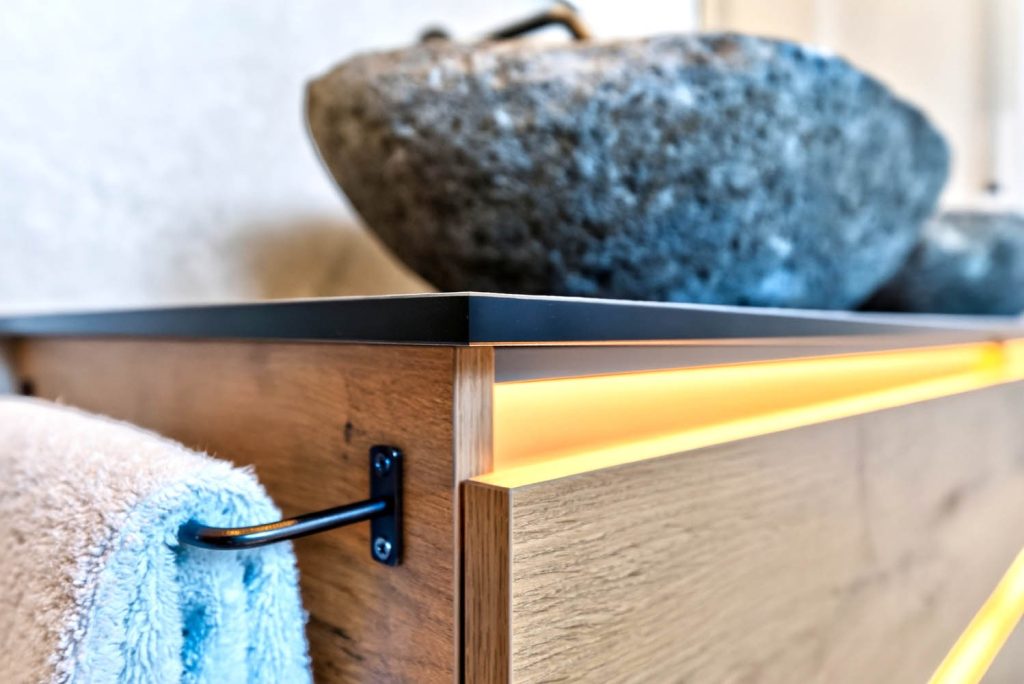 Detail des Holzunterschranks mit Lichtleiste und Handtuchhalter