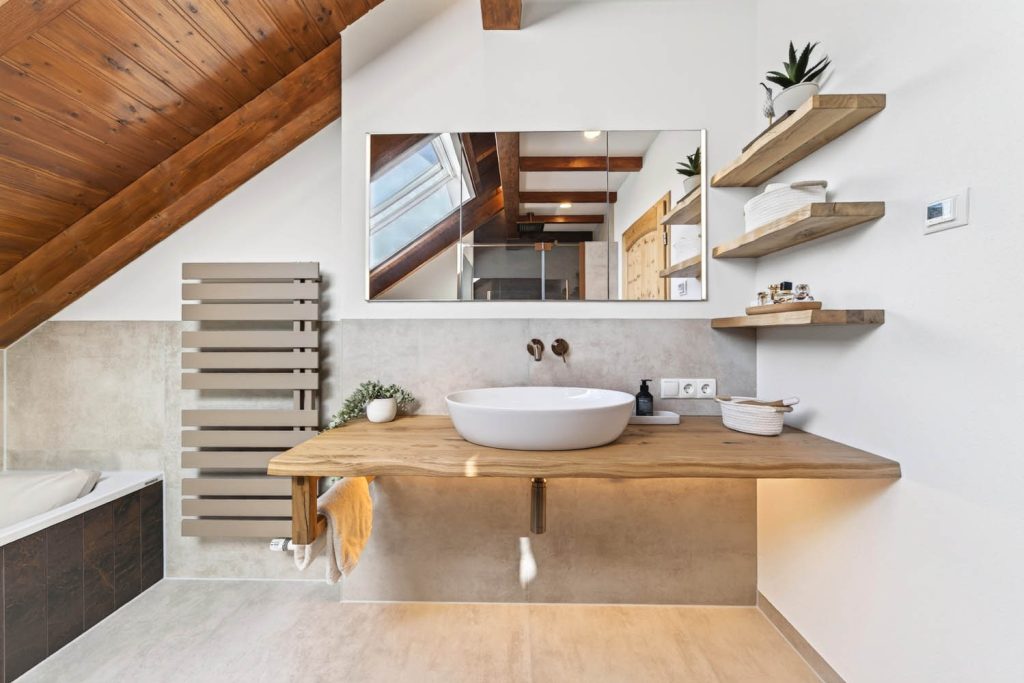 Massivholz-Waschtisch mit weißem Becken und schwebenden Holzregalen unter der Dachschräge