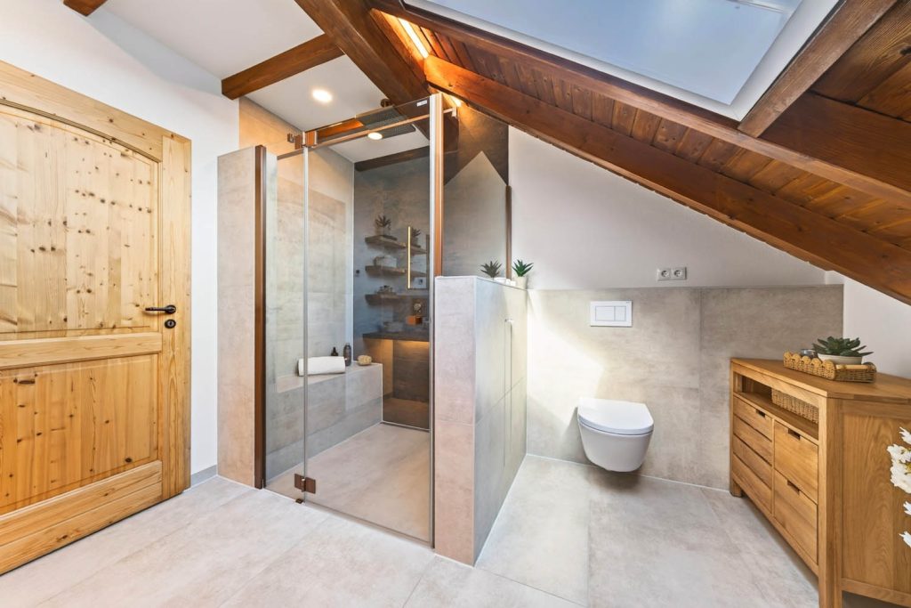 Glasdusche unter der Dachschräge neben dem WC-Bereich mit Holzkommode