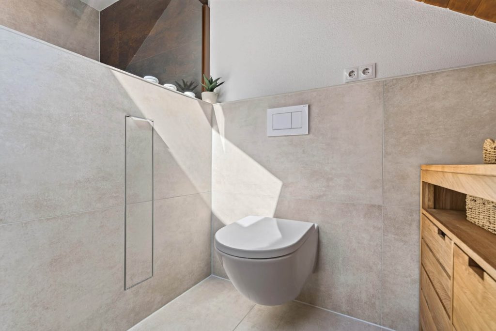 Wand-WC mit eingelassenem Wandschrank, Sonnenlicht auf hellen Fliesen in Steinoptik