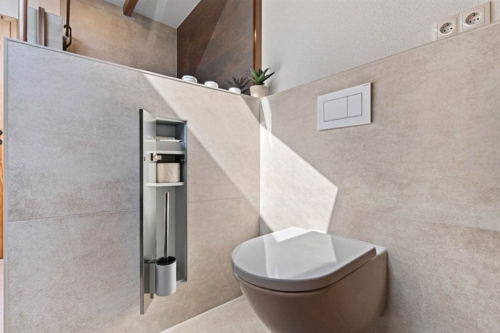 Einbaufach mit Edelstahlrahmen für Papier und WC-Bürste neben dem Wand-WC