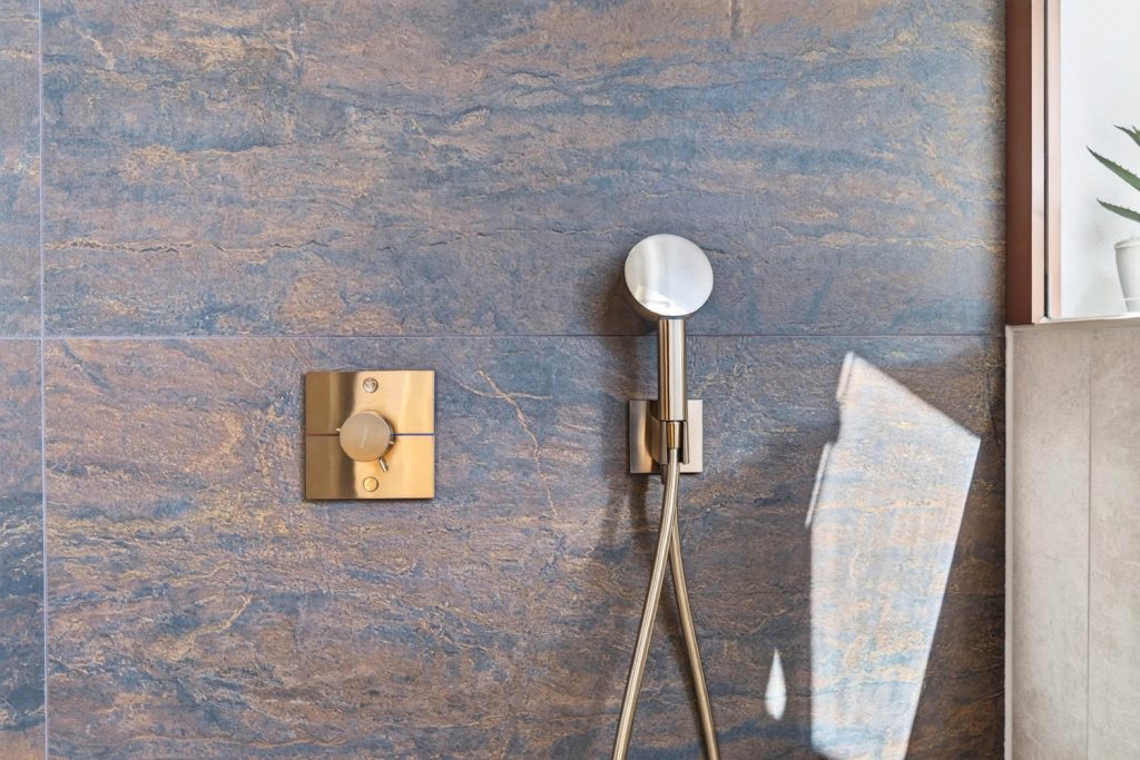 Thermostat und Handbrause in Kupfer auf Fliesen in Rostoptik