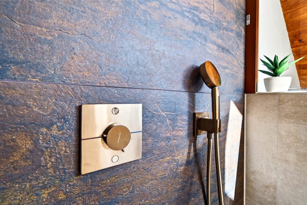 Thermostat in Kupfer mit Handbrause an der Rostoptik-Wand