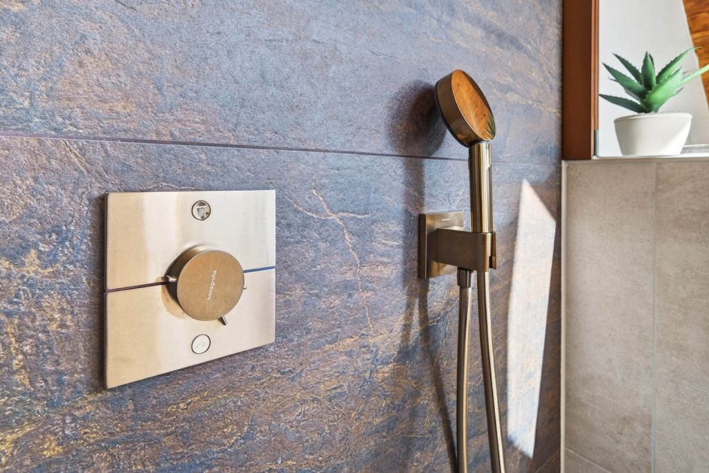 Detail des Thermostats in Kupfer neben der Handbrause