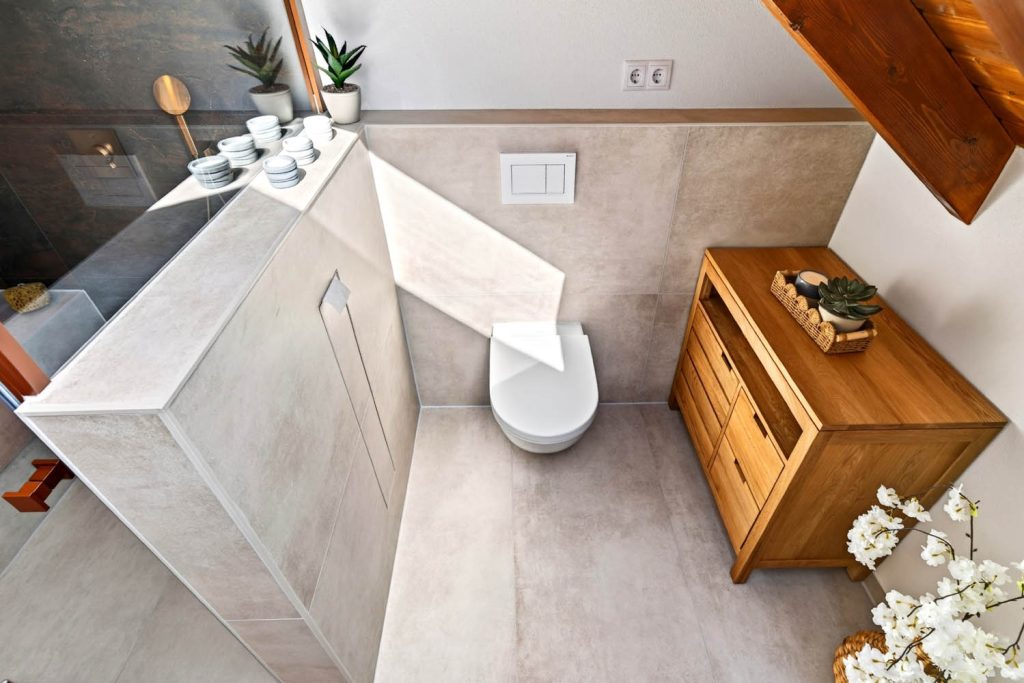 Vorwand mit WC, Holzkommode und Blick in die Dusche von oben