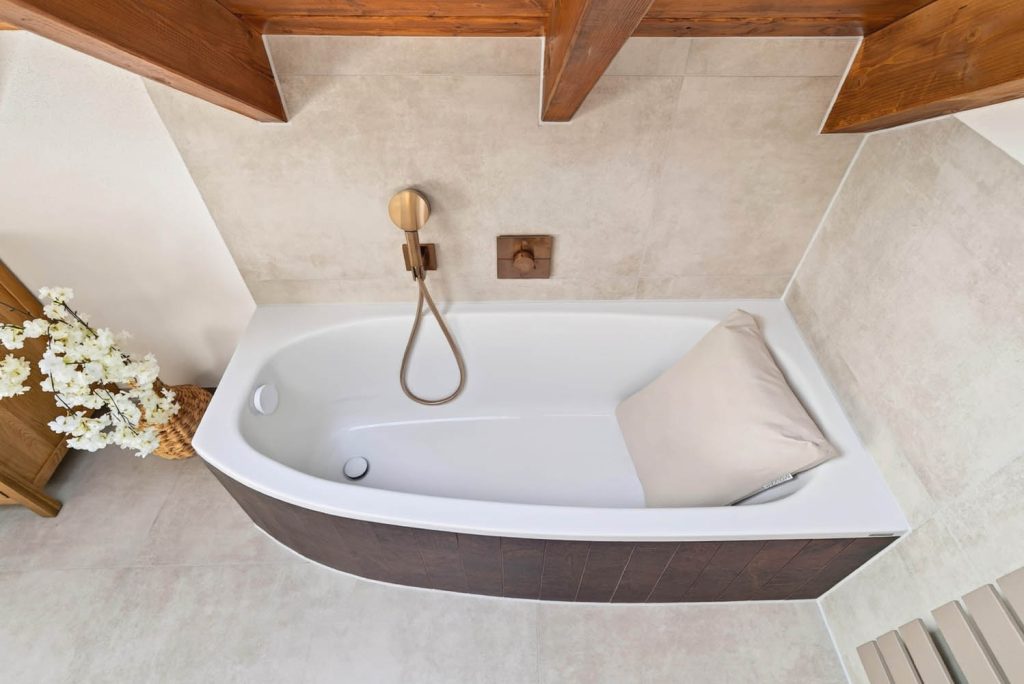 Eckbadewanne mit Kissen und Kupferarmatur von oben