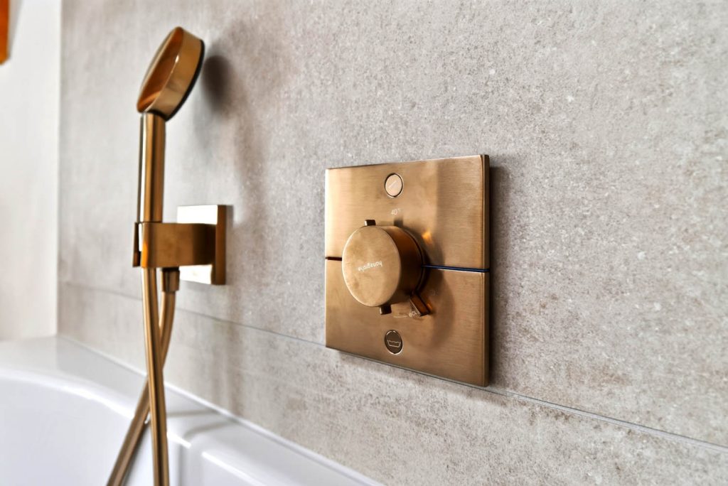 Wannenthermostat und Handbrause in Kupfer über dem Wannenrand