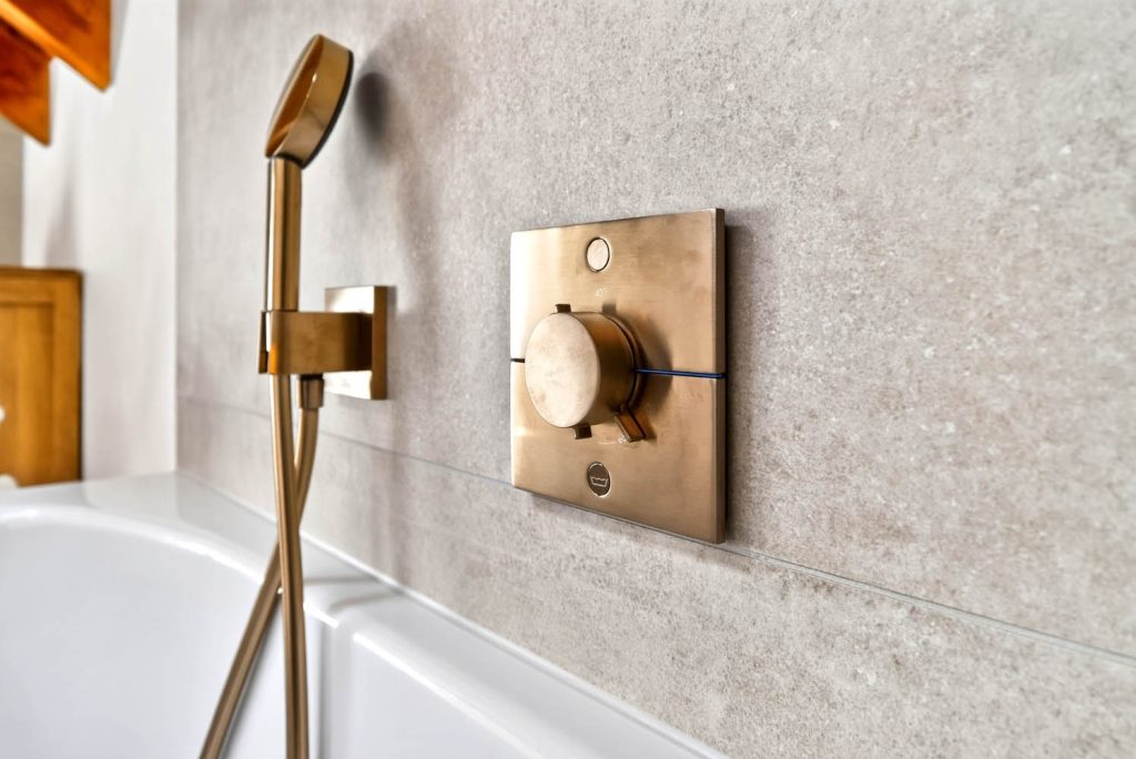 Detail des Thermostats in Kupfer an der Fliesenwand