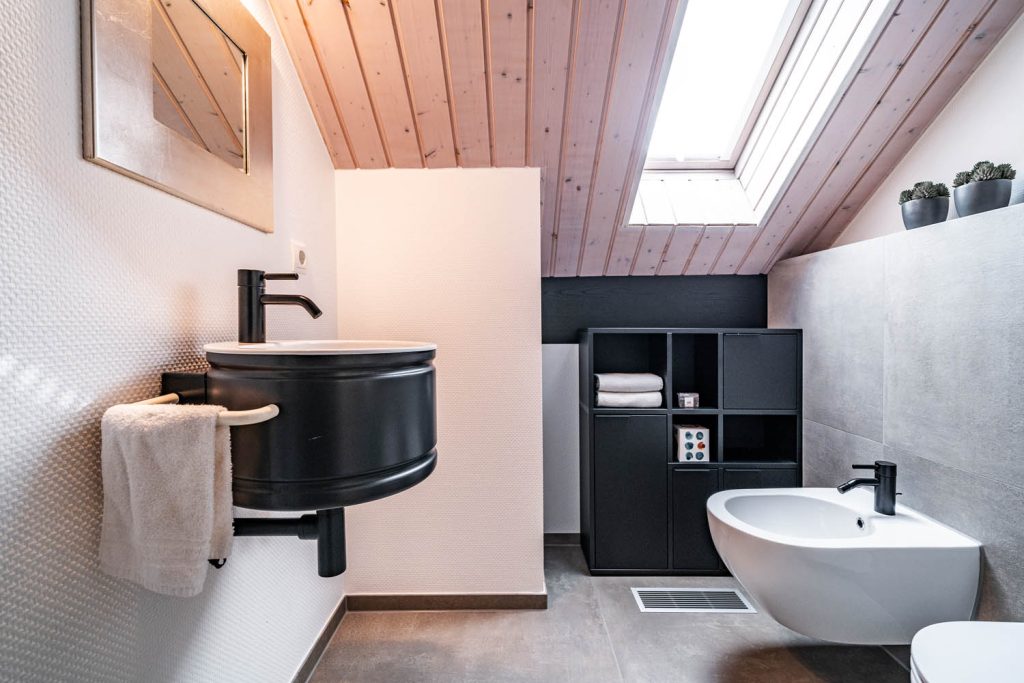 Gäste-WC unter der Dachschräge mit schwarzem Waschtisch, Regal und Bidet