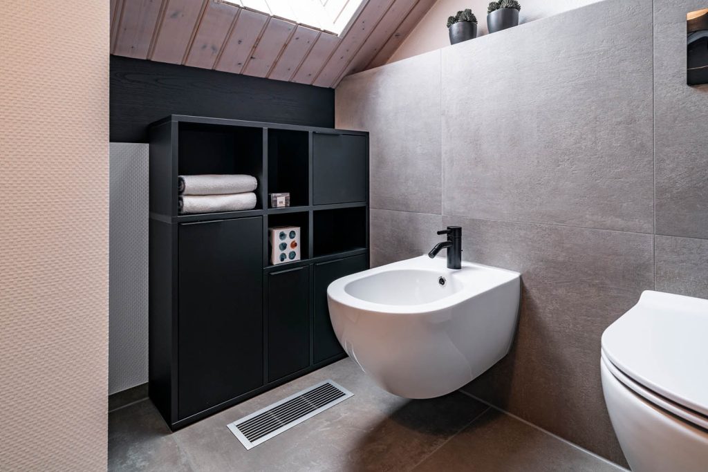Schwarzes Regal mit Handtüchern neben dem Bidet unter der Holzdecke