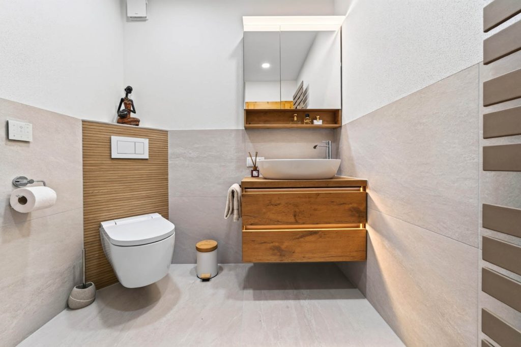 Wand-WC vor Vorwand mit Holzlamellen, daneben Waschtisch mit Spiegelschrank