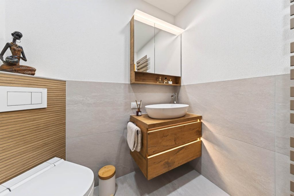 Waschtisch mit Aufsatzbecken und Spiegelschrank, links Vorwand mit Holzlamellen