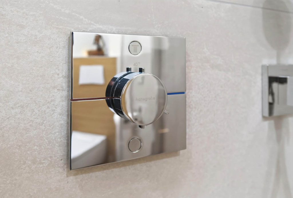 Detail des verchromten Thermostats neben der Brausehalterung